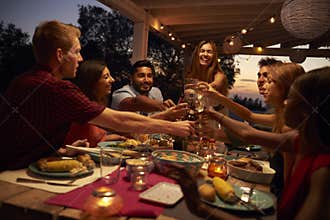 Friends make a toast at a dinner party on a patio, close up