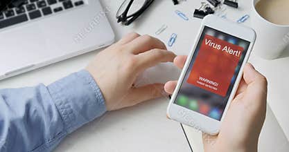 Man holds smartphone with virus alert warning sign on the display