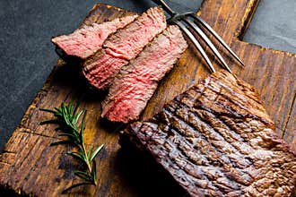 Sliced grilled medium rare beef steak served on wooden board Barbecue, bbq meat beef tenderloin. Top view, slate background