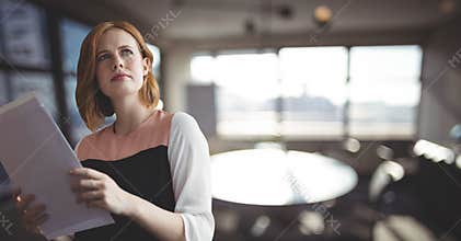 Confused business woman holding files against office background