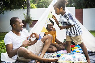 Black family enjoying summer together at backyard blowing soap b