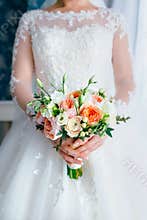 Beautiful bridal bouquet with white roses and peach peonies in a bride hands in white dress. Wedding morning. Close-up