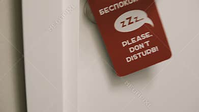 Close-up view of female coming into her room in hotel and puts on the knob the door hanger, asking do not disturb her.