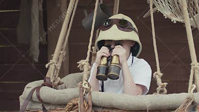 Small kid playing explorer, looking through binocular standing in air balloon