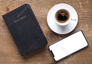 Holy Bible and smartphone with black coffee cup