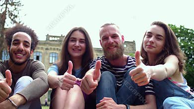 Cheerful students showing thumbs up.