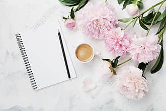 Morning coffee mug for breakfast, empty notebook, pencil and pink peony flowers on white stone table top view in flat lay style.
