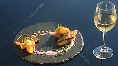 A dish of haute cuisine. close-up. Fish with young potatoes. mullet. With a glass of white wine. Primorsik restaurant