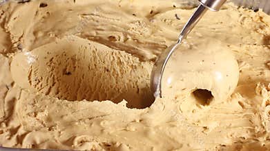Strawberry ice cream scooped out of container spoon is a ball. Close-up of caramel ice cream in a large box. Round spoon