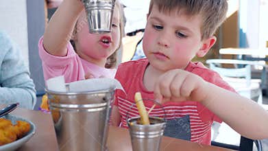 Female child gives male child sauce for French fries, Boy and girl are having an appetizing dinner in restaurant