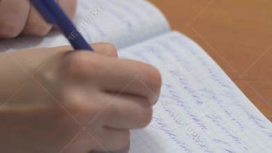 Female hands with pen writing on notebook. Close up of woman`s hands writing in spiral notepad placed on wooden desktop