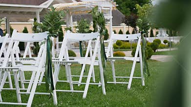 Wedding set up in garden, park. Outside wedding ceremony, celebration. Wedding aisle decor. Rows of white wooden empty