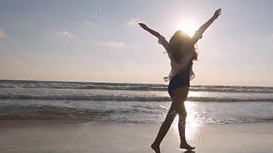 Happy woman running and spinning on the beach near the ocean. Young beautiful girl enjoying life and having fun at sea