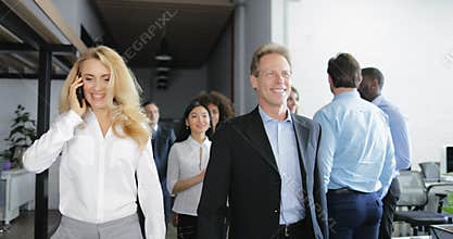 Businesswoman make phone call walking with happy smiling business people team in modern creative office