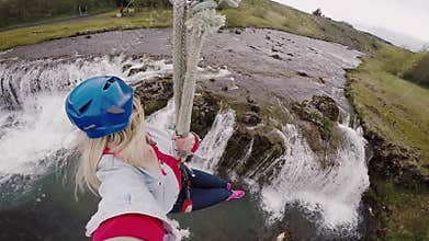 Selfie on action camera of young beautiful woman flying downhill on bungee through the rope way over the river.