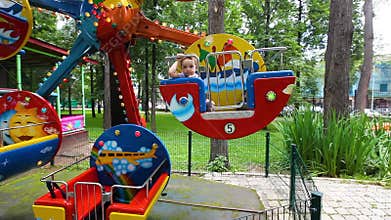 Little girl rides a carousel. Park of attractions