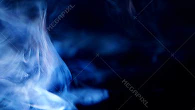 Closeup of blue light rays from projector, spreading through smoke