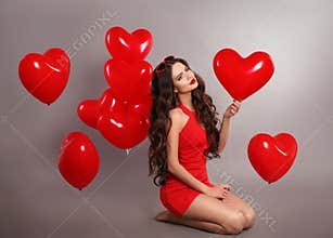 Pretty cute brunette girl in red with heart balloons posing isol