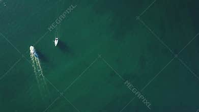 4K. Flight over marina with floating yachts and lighthouse, aerial bird`s eye view at sunset