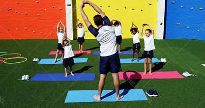 Yoga instructor instructing children in performing exercise