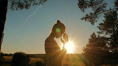 Sporty woman practicing yoga in park at sunset