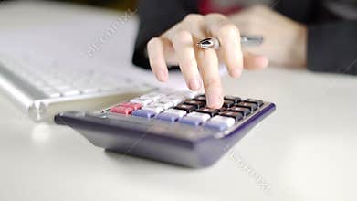 Woman accountant calculating and taking notes on white desk in office
