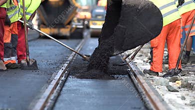 Steamroller workers construct asphalt road and railroad lines