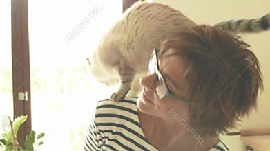 Domestic cat playing on the shoulder of smiling beautiful woman. Indoors setting. Toned image, vintage style, retro filter, backli