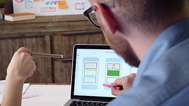 Mobile app developers discussing mobile app prototype on the computer screen
