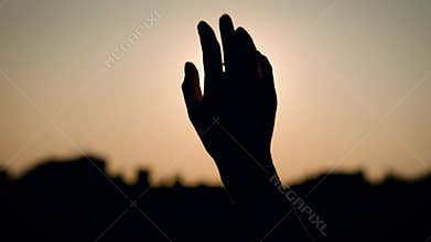 Close up shot of the hand of a girl or woman who moves her against the sun, silhouette of fingers and hands on the