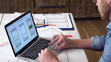 UX designer creating mobile app prototype on his laptop computer