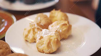 Sugar powder pour on profiteroles on table with lots of baking products
