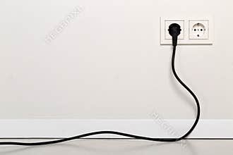 Black power cord cable plugged into european wall outlet on whit