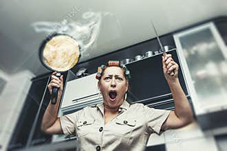 Woman in the kitchen with a frying pan with a hot pancake and a