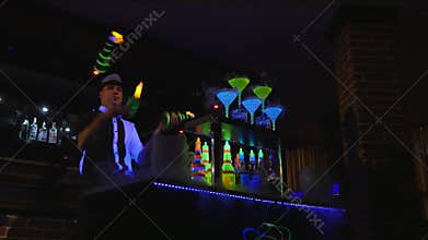 Young, attractive professional barman, bartender making cool, professional, amazing tricks with two bottles, catching on