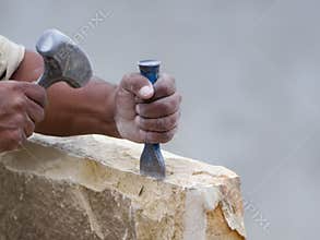 Stone mason chiseling a block of stone