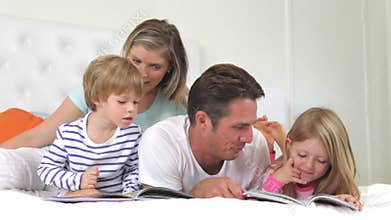 Family Lying In Bed Reading Books Together