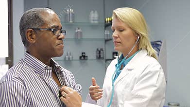 Doctor Listening To Male Patient's Chest With Stethoscope