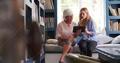 Daughter Helping Senior Mother With Digital Tablet At Home