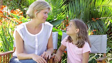 Mother And Daughter Sitting In Garden Chairs And Talking