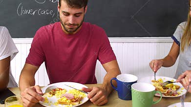 Group Of Friends Eating Cooked Breakfast In Kitchen Together