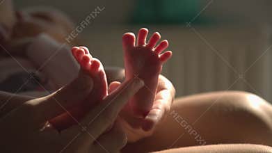 Mom hands foot massage newborn baby