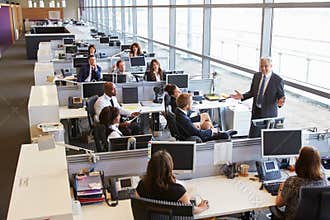 Senior male manager addressing workers in open plan office