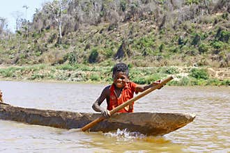 Young Malagasy african boy rowing traditional canoe
