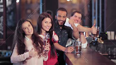 A group of friends at the bar with a beer smiling