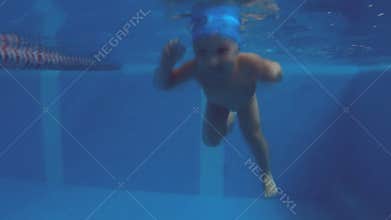 Cute baby diving into a pool and swimming under water