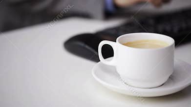 Close up of businessman typing and drinking coffee