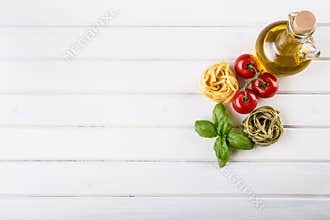 Italian and Mediterranean food ingredients on wooden background.Cherry tomatoes pasta, basil leaves and carafe with olive oil.