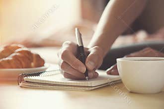 Pen writing on notebook with coffee