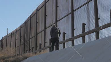 Man Walks Casually Along the US and Mexico Border Fence